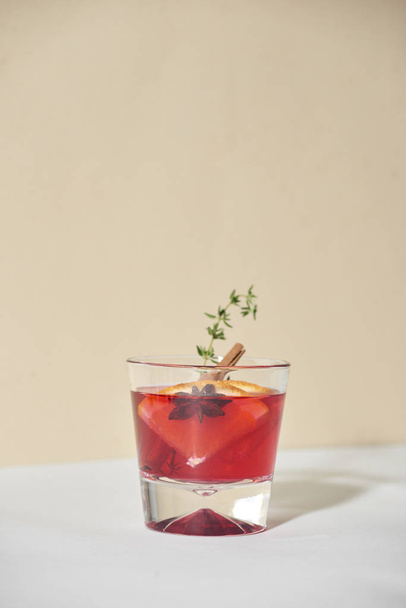 Orange cocktail with rum, liquor, pear slices and thyme in glass on white table - Photo, Image