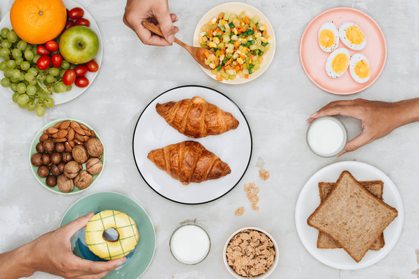 Healthy breakfast ingredients on grey tabletop with human hands - Fotó, kép