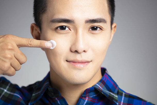  closeup young man applying facial cream - Foto, Imagem
