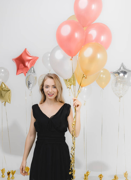 Beautiful young caucasian woman in black dress, happy smiling holding colorful balloons at fun party, studio portrait shot  white background. - Фото, зображення