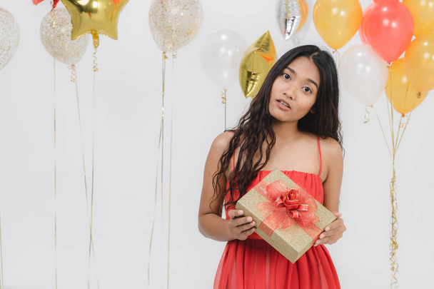 Atrakcyjna młoda kobieta azjatyckich nosi czerwoną sukienkę podekscytowany z jej dar, szczęśliwy zabawa Strona, portret strzał białe tło uroczysty balon. - Zdjęcie, obraz