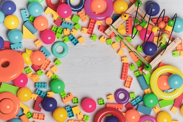 Zblízka shora pohled záběr pestrobarevné hračky, bloky, kroužky, propletené lego, dřevěné cihly, stavební herní kousky dětí uspořádat hračky v různých tvarech s kopírovacím prostorem v centrální části - Fotografie, Obrázek