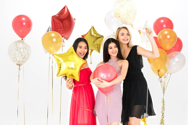 Ποικιλομορφία των νεαρών γυναικών ευτυχής να διασκεδάσουν μαζί στο κόμμα, λευκό φόντο και πολύχρωμα μπαλόνια εορταστική. - Φωτογραφία, εικόνα