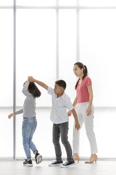 Asian woman in pink shirt teach kids to playing something , they stand in front of big white window. - Photo, image