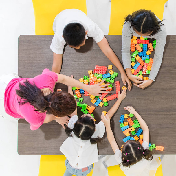 Flat lay shot of Asian teacher play colorful build blocks toy with Asian kids together, concept for classroom. - Photo, Image