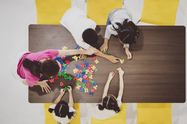 Group of kids and teacher playing colorful toys in classroom. Concept for happy and funny learning, brain development activities in school free time. - Фото, зображення