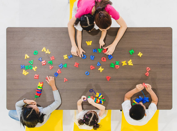 Group of kids and teacher playing colorful toys in classroom. Concept for happy and funny learning, brain development activities in school free time. - Photo, Image