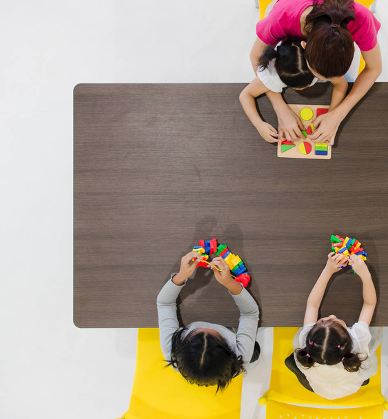 Group of kids and teacher playing colorful toys in classroom. Concept for happy and funny learning, brain development activities in school free time. - Fotografie, Obrázek