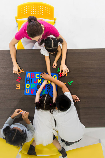 Flat lay shot di insegnanti asiatici giocare colorato Alfabeto puzzle giocattolo con studenti asiatici insieme, concetto per l'aula
. - Foto, immagini
