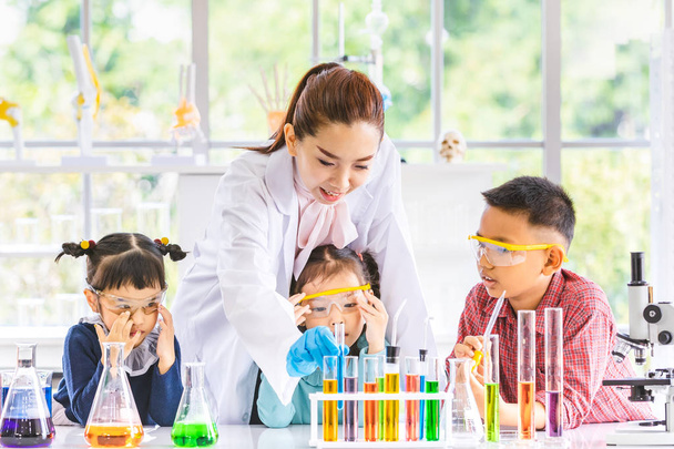 Tiede opettaja opettaa Aasian opiskelijoille kemikaaleja, savu kellua ulos isku, värikäs koeputki ja mikroskooppi pöydällä laboratoriohuoneessa, käsite tutkimuksen laboratoriohuoneessa
. - Valokuva, kuva
