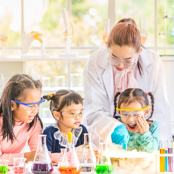 Science teacher teach Asian students in laboratory room, smoke float out of bowl, they excited, colorful test tube and microscope on table in laboratory room, concept for study in laboratory room. - Photo, Image