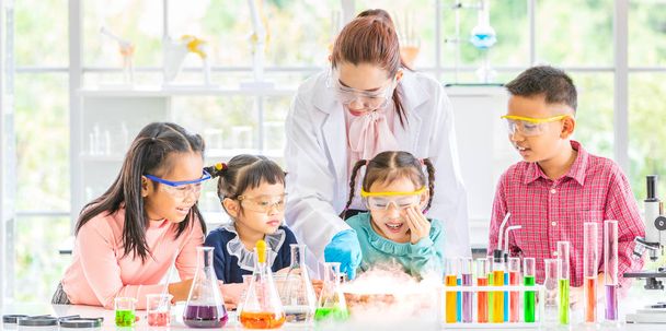 Science teacher teach Asian students in laboratory room, smoke float out of bowl, they excited, colorful test tube and microscope on table in laboratory room, concept for study in laboratory room. - Photo, Image