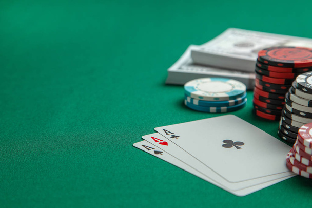 Концепция азартных игр в казино, спортивный покер. Игровые карты и цветные фишки с наличными долларами на зеленом игровом столе
 - Фото, изображение