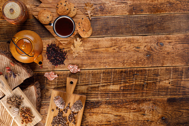 Autumn winter still life. Teapot with tea on a wooden table with honey and oatmeal cookies and pine nuts. The apartment lay. The space under the text. Comfort - Photo, image