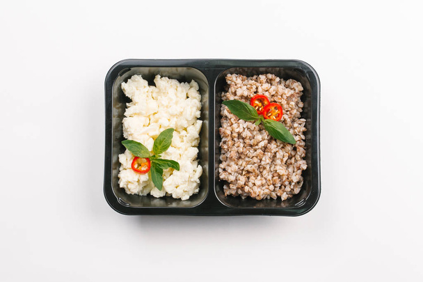 Top view of proper nutrition of buckwheat and chese in box on white background - Photo, Image