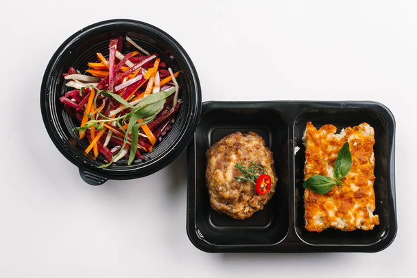 Vue du dessus de la bonne nutrition de la casserole et boulette de viande avec salade de légumes dans des boîtes sur fond blanc
 - Photo, image