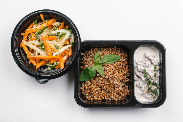 Top view of proper nutrition with buckwheat and meat in creamy sauce with vegetables salad in boxes on white background - Photo, Image