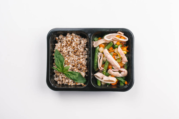 Вид зверху на правильне харчування салату з кальмарами та гречки в коробці на білому тлі
 - Фото, зображення