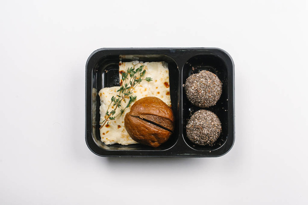 Vista superior de la nutrición adecuada de cazuela con queso, bollo y bolas de sésamo en caja sobre fondo blanco
 - Foto, imagen