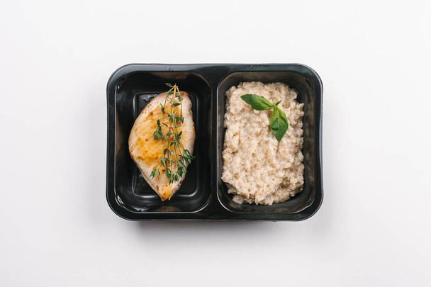 Ansicht der richtigen Ernährung mit Haferbrei und gegrilltem Fleisch in Schachtel auf weißem Hintergrund - Foto, Bild
