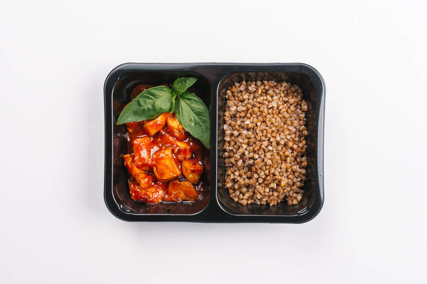 Vista superior da nutrição adequada de trigo sarraceno e carne em molho na caixa no fundo branco
 - Foto, Imagem