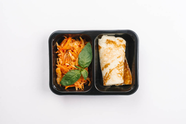 Vista superior de la nutrición adecuada con ensalada de verduras y panqueque en caja sobre fondo blanco
 - Foto, Imagen