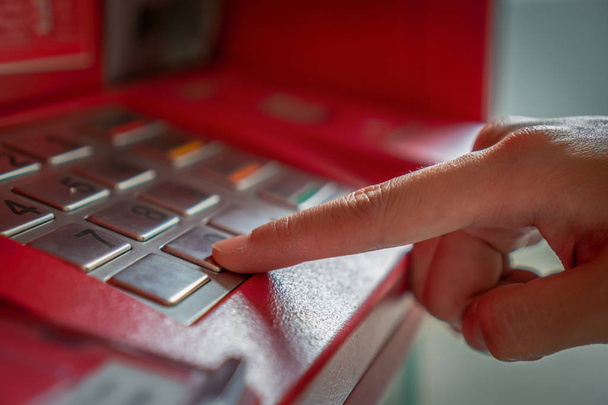 Fermer la main en appuyant sur et caché le code secret lors du retrait de l'argent via un distributeur automatique de billets, concept de machine de guichet automatique d'affaires
 - Photo, image