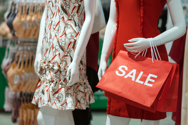 Onderdeel van vrouwelijke etalagepop gekleed in casual kleding houden de papieren boodschappentas van verkoop in het winkelen warenhuis voor winkelen, bedrijfsconcept mode en reclame - Foto, afbeelding