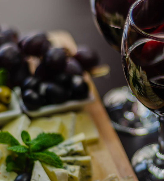 Kırmızı şarap ve bir tahta masa, lezzetli Aperatif, sağlıklı ve özel gıda üzerinde farklı peynir kümesi - Fotoğraf, Görsel