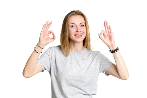 Portrait of a young woman who shows fingers a percent sign or an OK symbol on a white background. - Фото, зображення