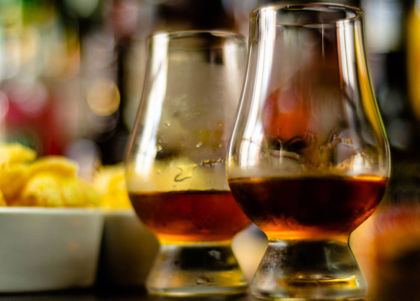 Glas Whisky mit Eiswürfeln und salzigen Snacks auf dem Hintergrund der Bar, Party-Time - Foto, Bild