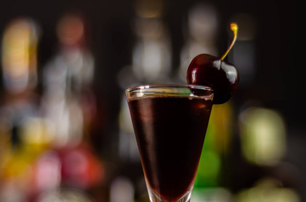 Cherry liqueur and juicy ripe cherries on the table in  the bar, an elegant serving of sweet drink in the restaurant, a traditional drink - Foto, immagini