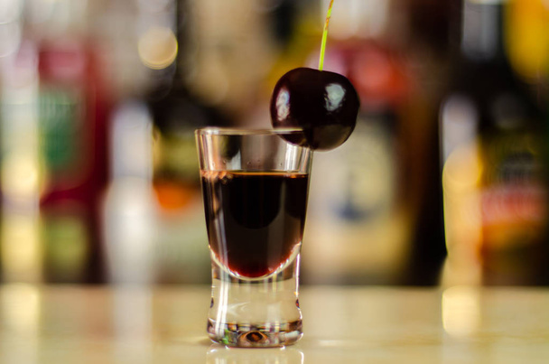 Třešňový likér a šťavnaté zralé třešně na stole v baru, elegantní servírovací sladké pití v restauraci, tradiční nápoj - Fotografie, Obrázek
