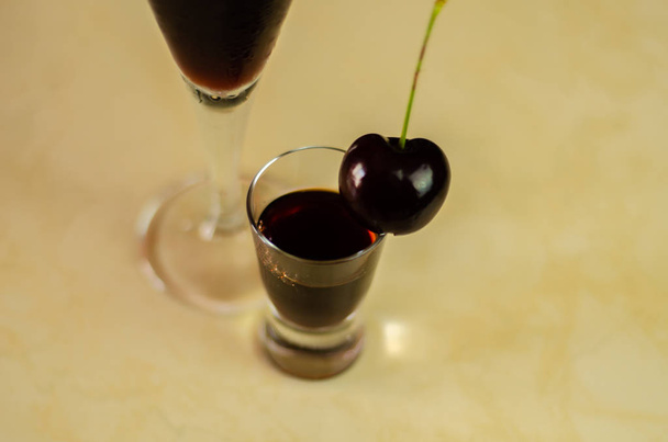 Likier wiśniowy i soczyste wiśnie dojrzałe na stole w barze, eleganckim podaniem słodki napój restauracja, tradycyjny napój - Zdjęcie, obraz