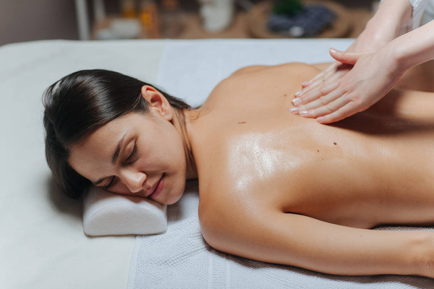 Young woman enjoying a back massage in a spa center. - 写真・画像