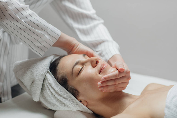 Jovem desfrutando de uma massagem facial em um centro de spa
. - Foto, Imagem