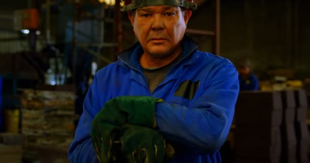 Male worker standing in helmet at workshop. Male worker holding metal rod 4k - Séquence, vidéo