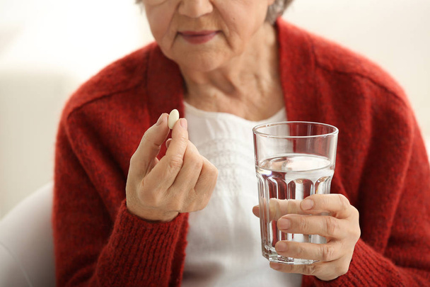 Mulher idosa tomando pílula, close-up
 - Foto, Imagem