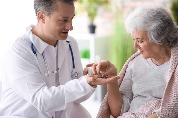 Doctor giving pills to elderly woman, indoors - Foto, afbeelding