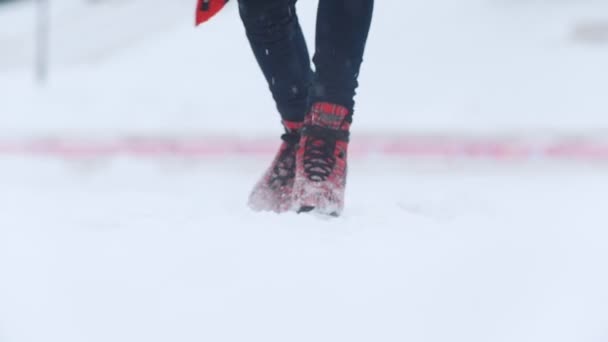 Egy fiatal nő korcsolyázás a világos piros korcsolyát kívül. Erős havazás. Lassú mozgás - Felvétel, videó