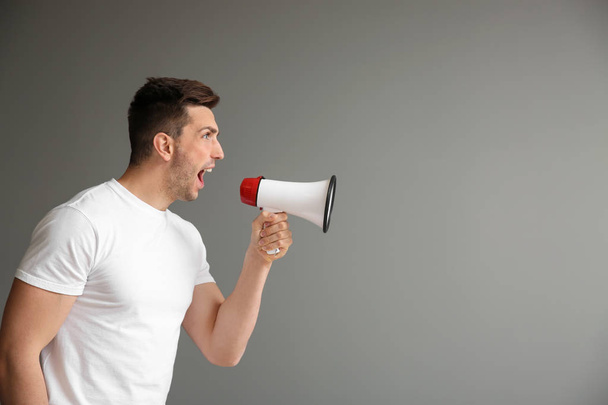 Кричащий молодой человек с мегафоном на сером фоне
 - Фото, изображение