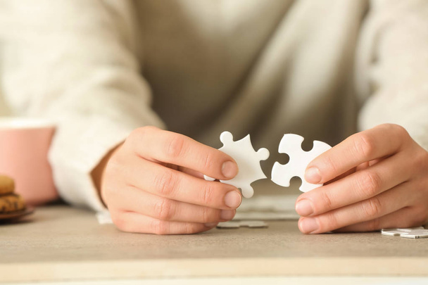 Woman assembling puzzle on table, closeup - Foto, afbeelding
