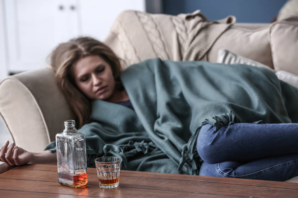 Sklo a láhev s alkoholem na stole opilá žena - Fotografie, Obrázek