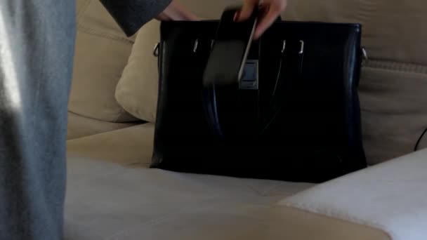 close view woman puts mobile phone into small black handbag - Filmati, video