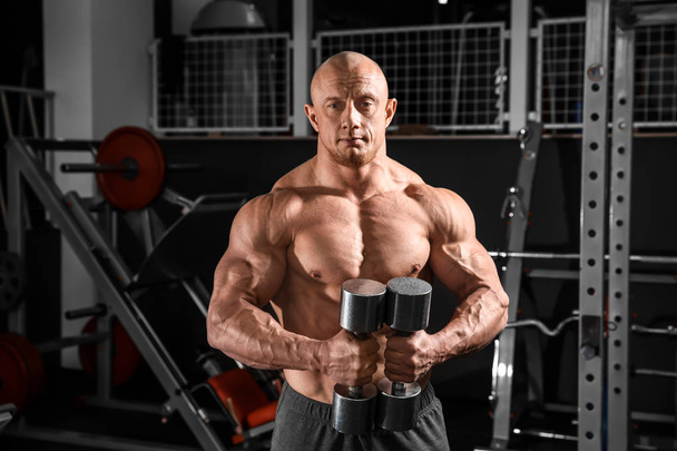 Muscular man training with dumbbells in gym - Photo, Image