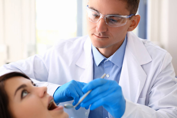 A woman at the reception of a male dentist examining - Photo, Image