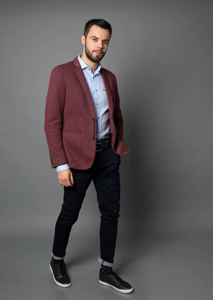 Fashionable young man on grey background - Foto, afbeelding
