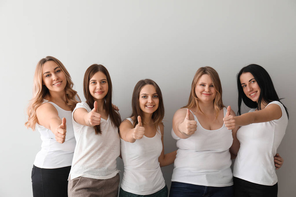 Mooie jonge vrouwen gebaar van duim-omhoog weergegeven op lichte achtergrond. Concept van lichaam positiviteit - Foto, afbeelding