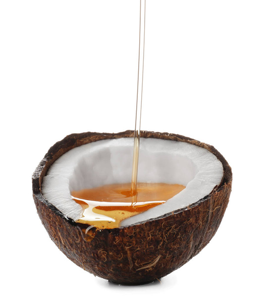 Nalévání oleje do polovinu z kokosu na bílém pozadí - Fotografie, Obrázek
