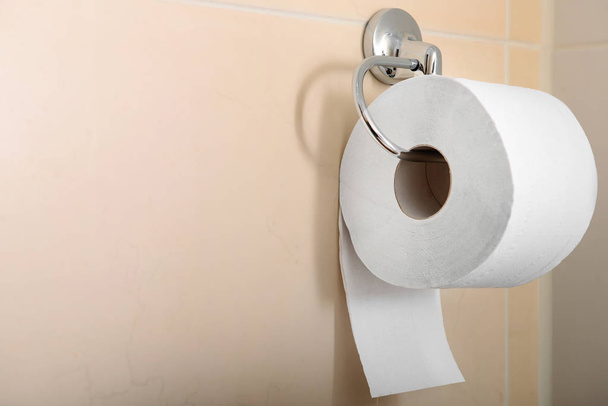 Рулон туалетной бумаги висит на стене в туалете
 - Фото, изображение